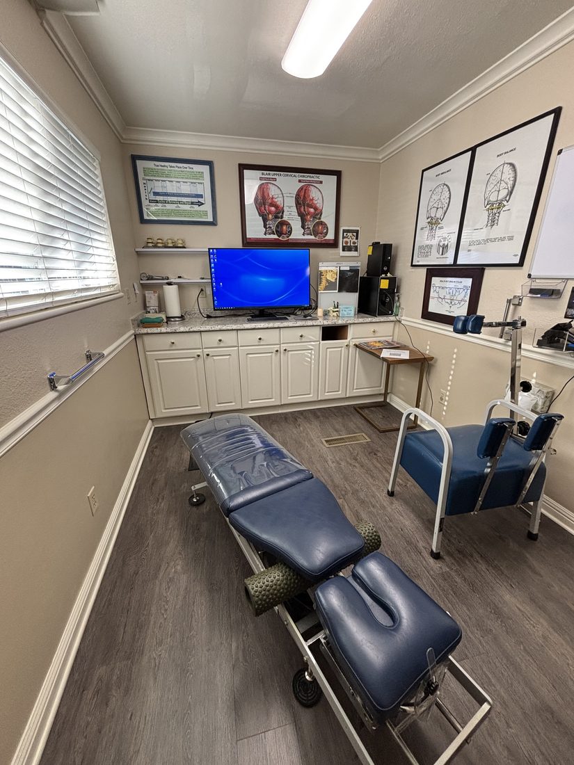 Adjusting room with a blue table and upper cervical charts on the wall